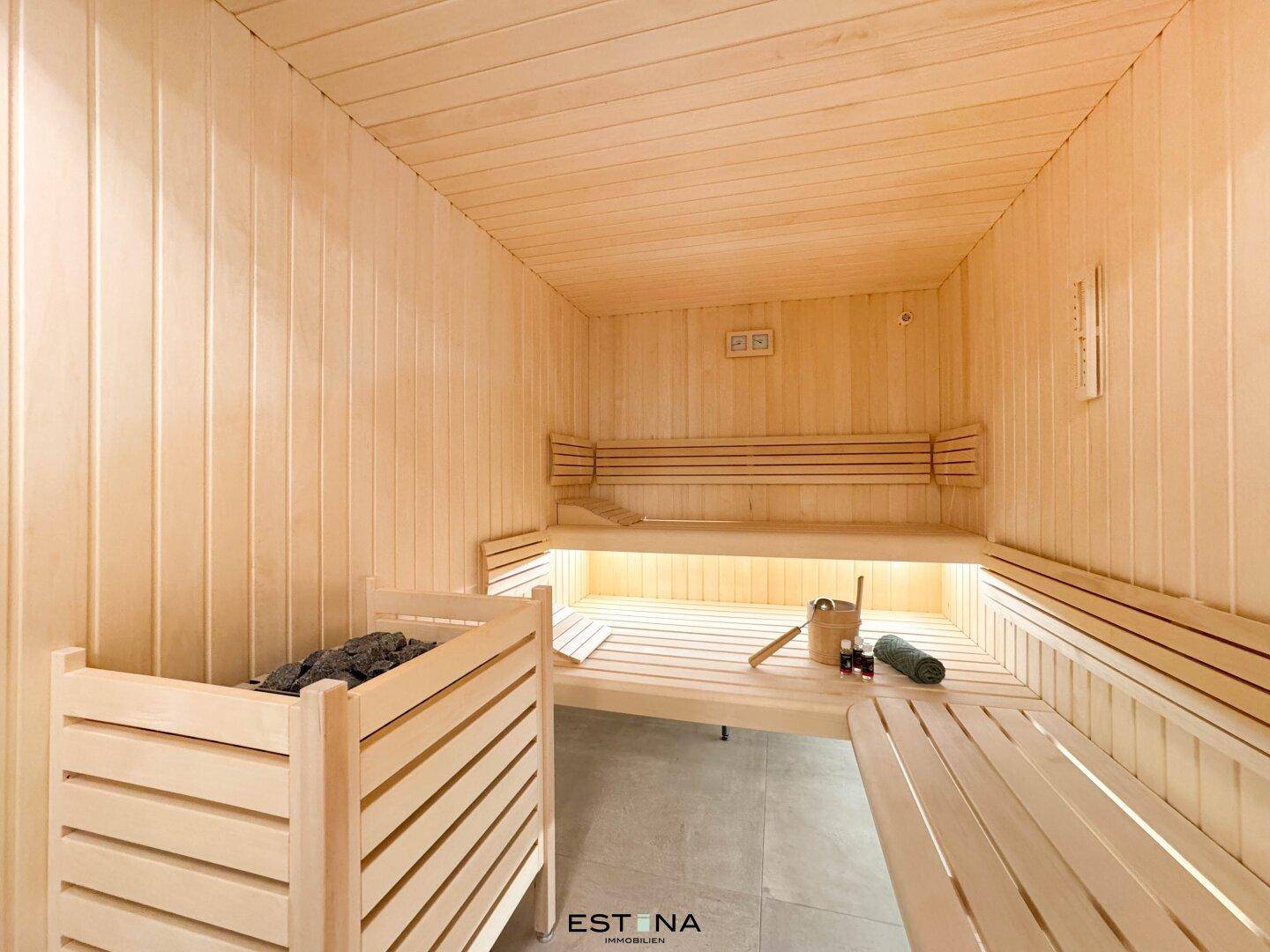 Moderne Holzsauna mit Bänken und traditionellem Saunaofen für Entspannung und Wellness.
