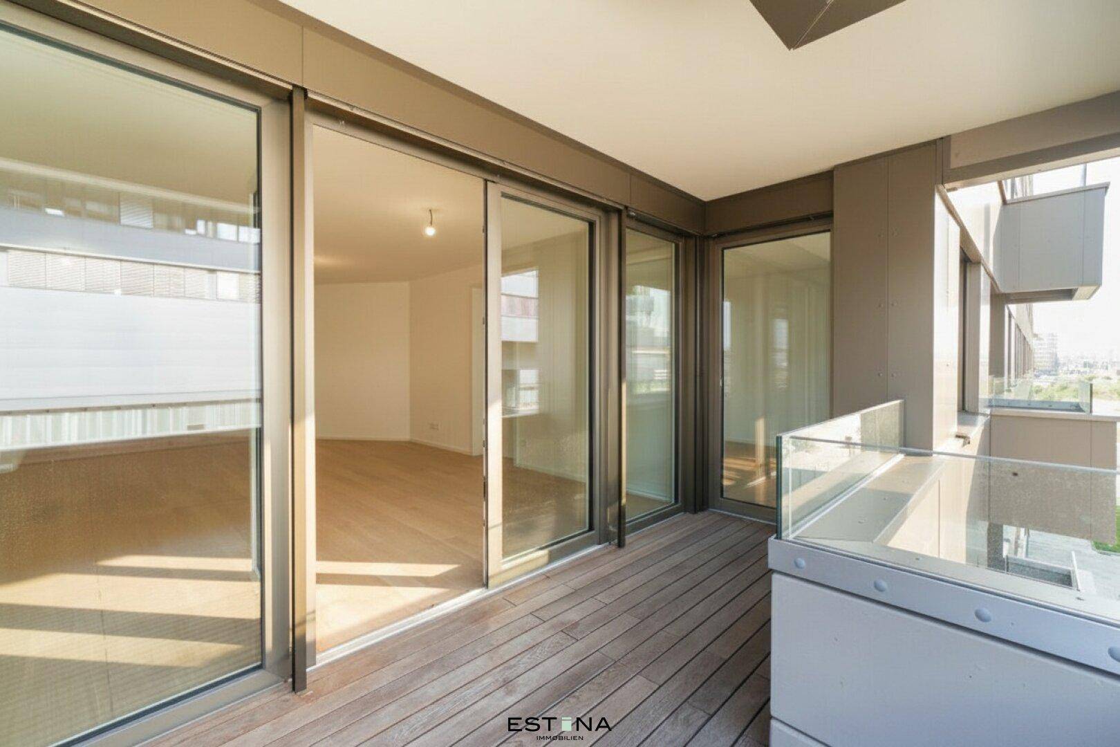 Geräumiger Balkon mit Holzboden und großen Glasschiebetüren, die den Innenraum mit dem Außenbereich verbinden.