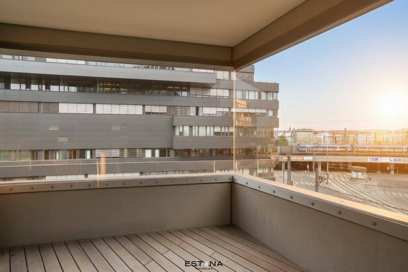 Leerer Balkon mit Holzboden und Glasbrüstung, bietet einen weiten Stadtblick.