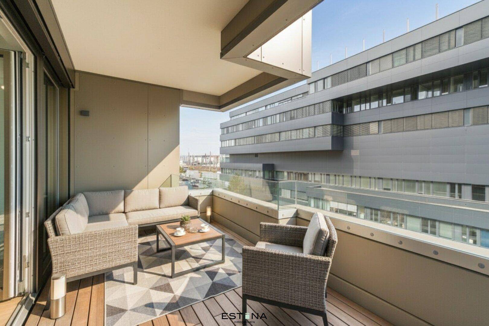 Möblierter Balkon mit Sitzgelegenheiten und Blick auf moderne Gebäude.