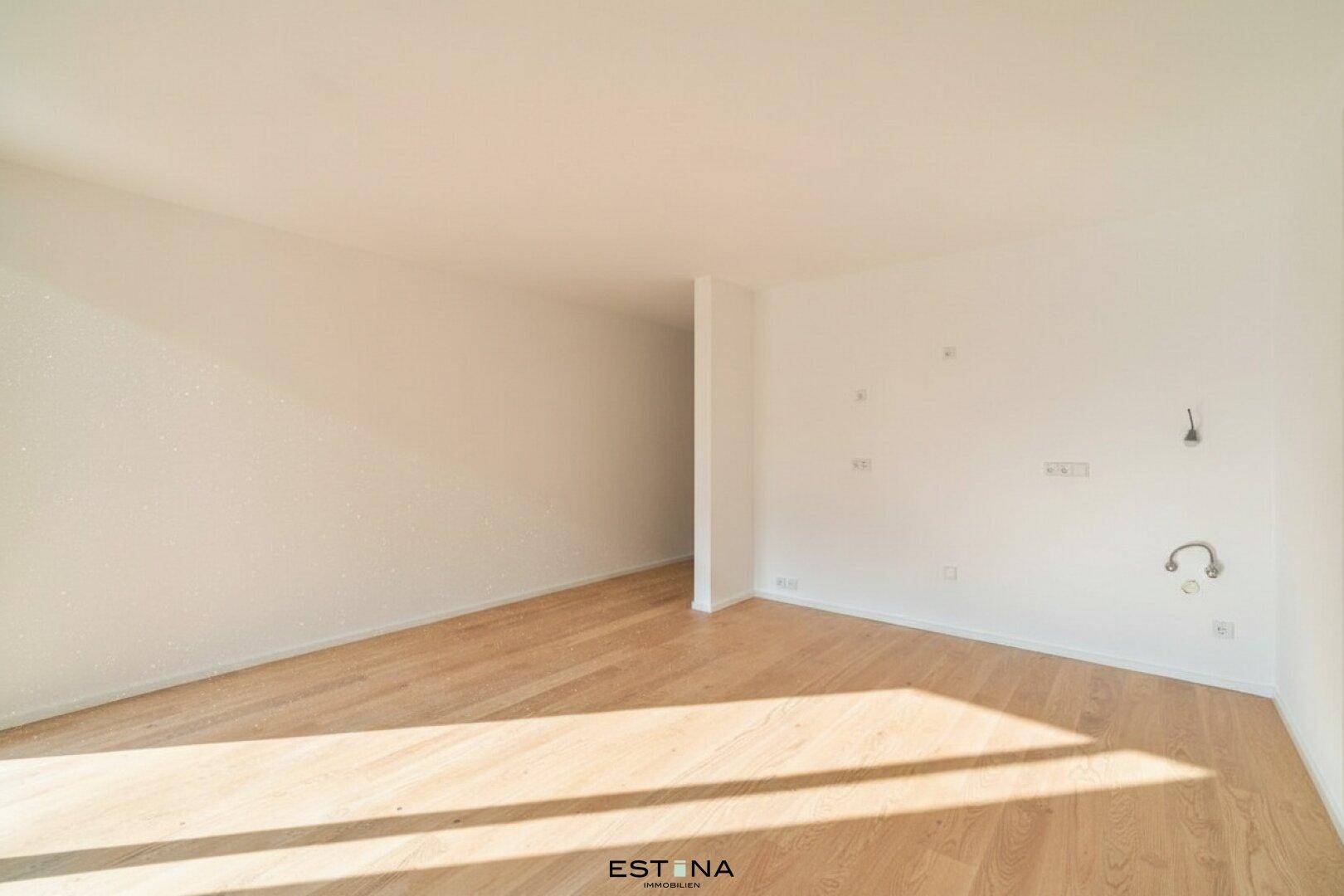 Geräumiger, unmöblierter Raum mit hellem Parkettboden und viel Tageslicht.
