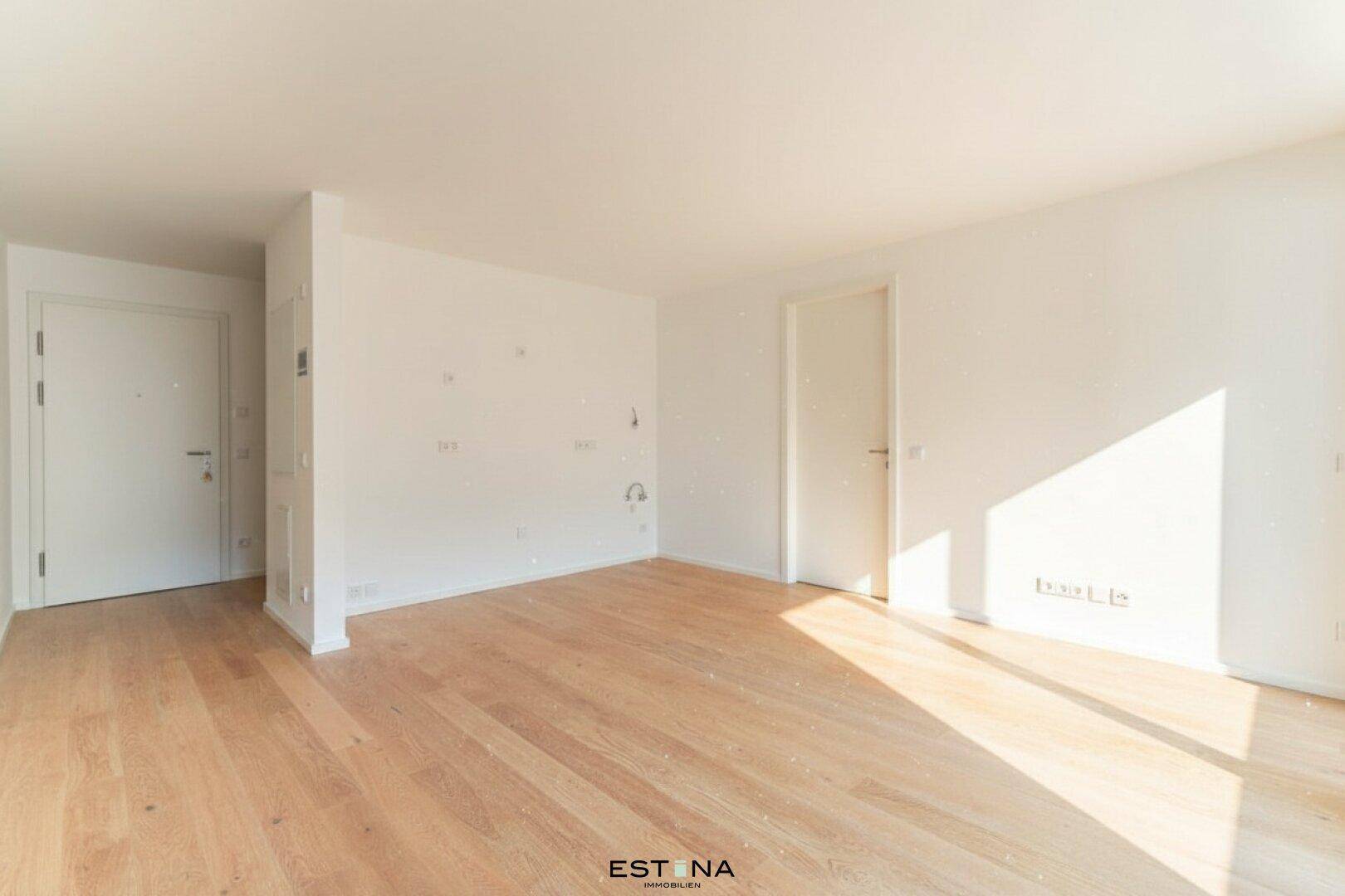 Geräumiger, unmöblierter Wohnraum mit hellem Parkettboden und viel Tageslicht.