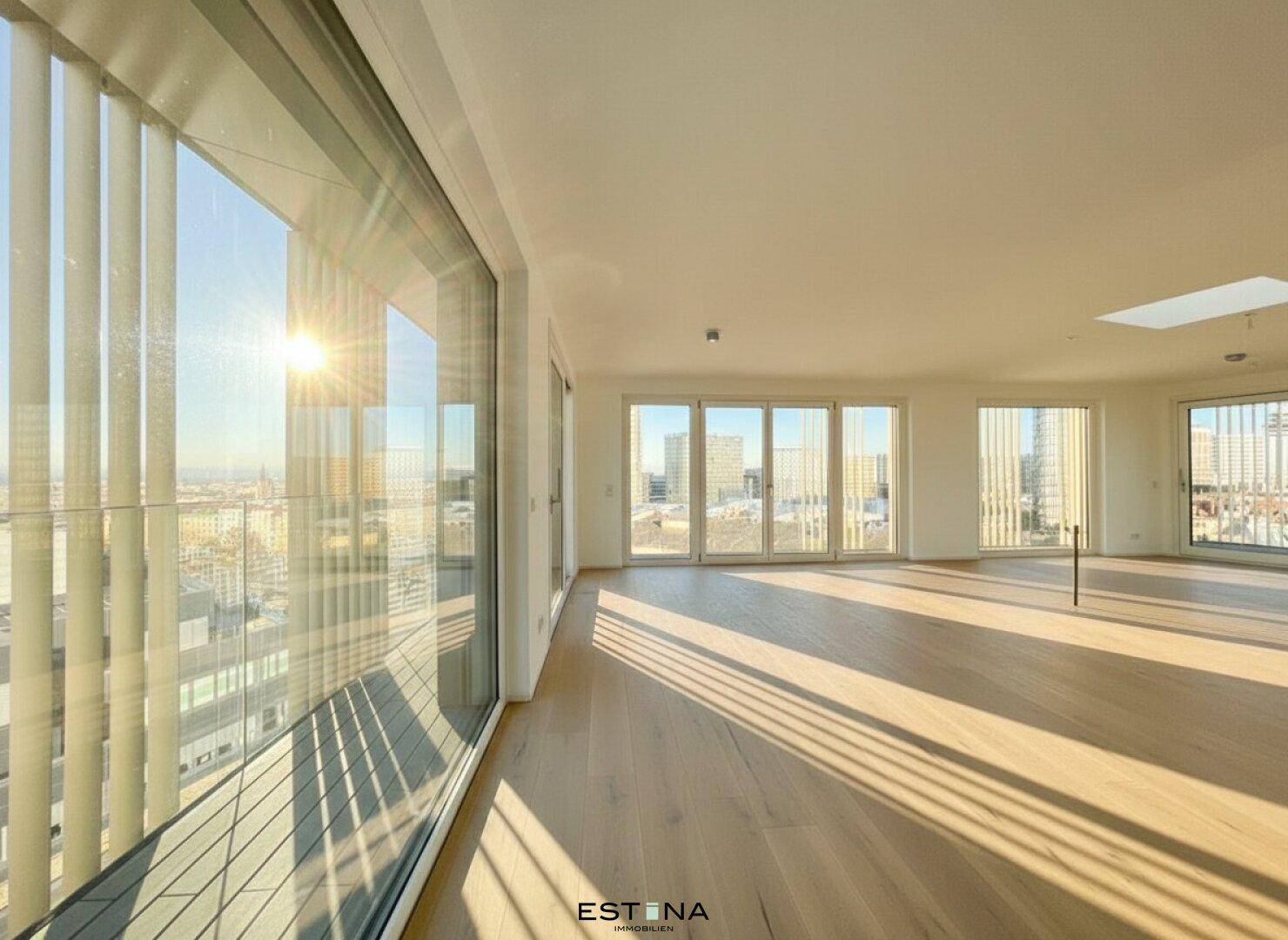 Lichtdurchfluteter, leerer Raum mit großen Fenstern und Panoramablick über die Stadt.