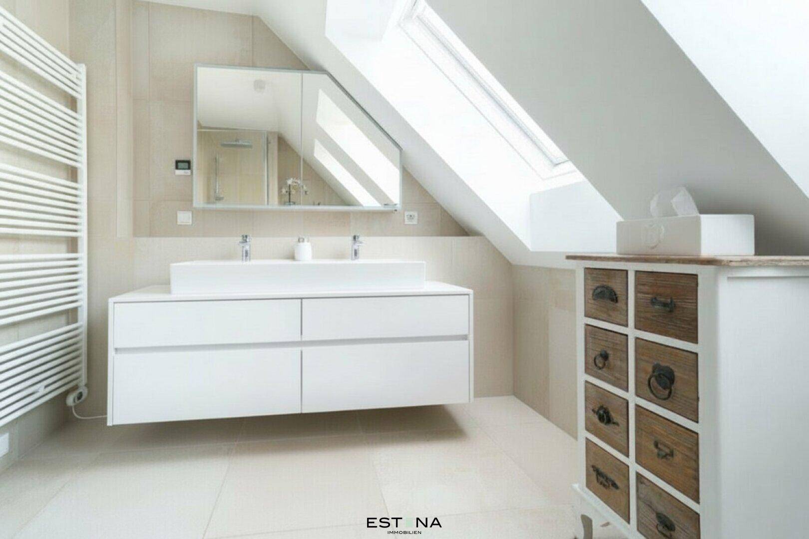 Helles Dachgeschossbad mit Doppelwaschbecken, Spiegelschrank und beheiztem Handtuchhalter.