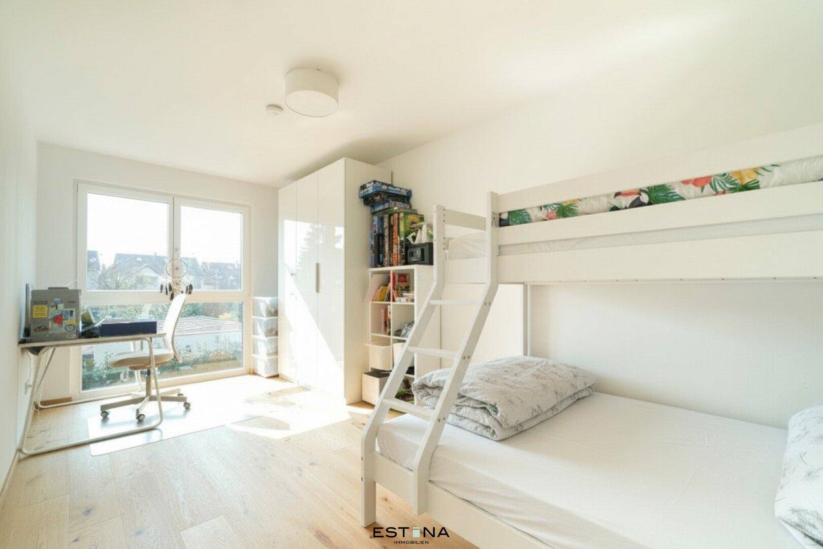 Kinderzimmer mit Etagenbett, Schreibtisch und großem Fenster für viel Tageslicht.