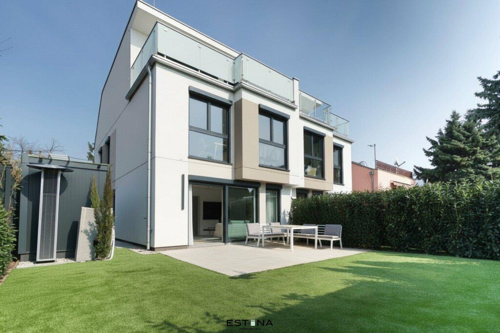 Moderne Hausfassade mit gepflegtem Rasen, Terrasse und Sitzgelegenheiten im Freien.