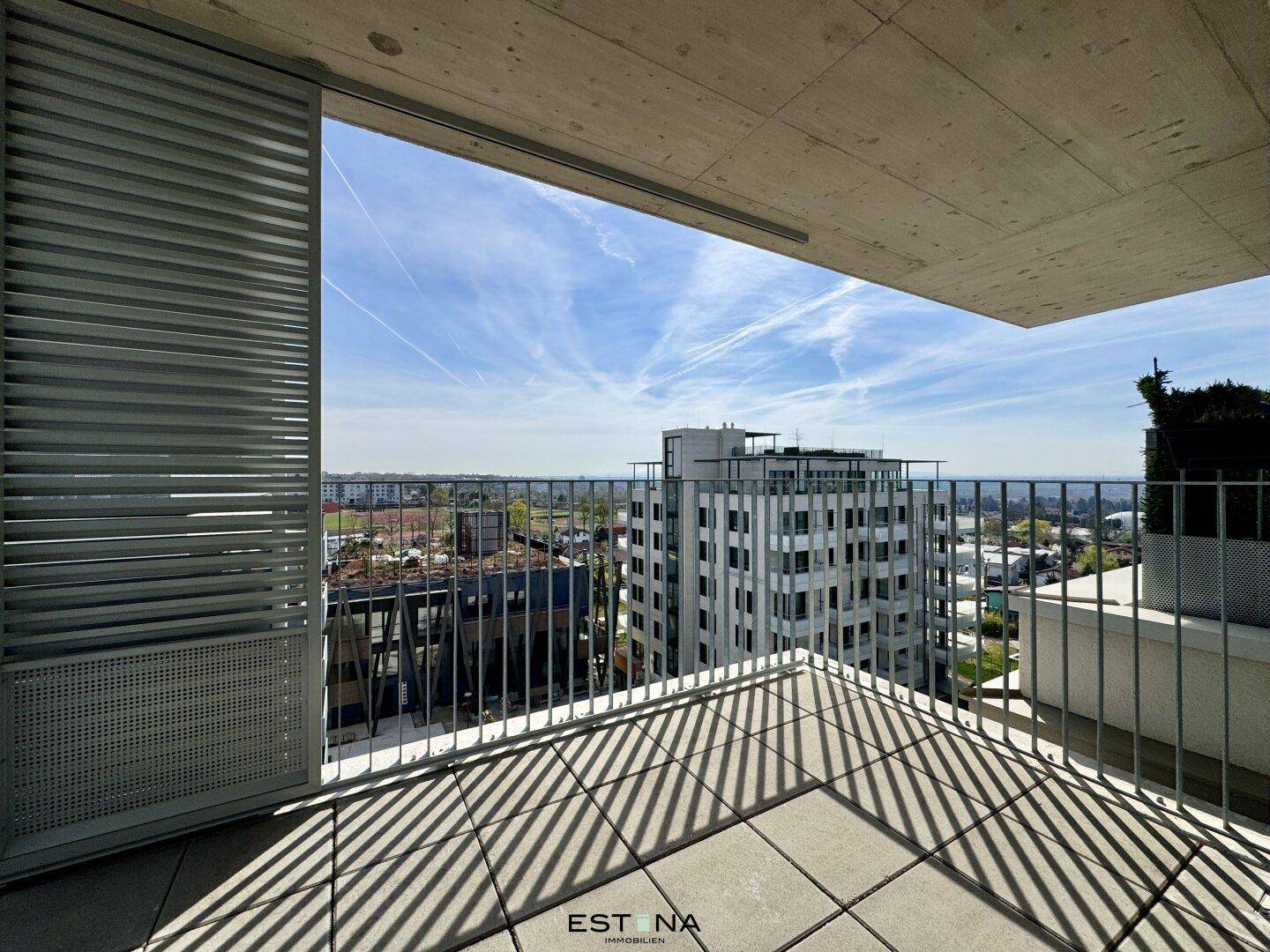 Geräumiger Balkon mit Fliesenboden und weitem Blick über die Stadt und die umliegende Landschaft.
