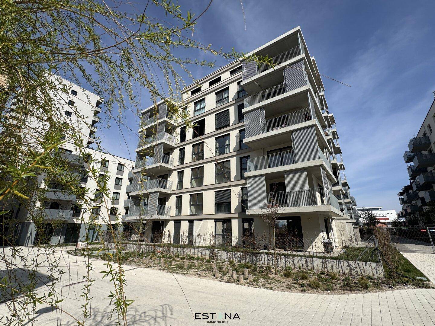 Modernes Mehrfamilienhaus mit mehreren Balkonen und gepflegter Außenanlage in sonniger Umgebung.
