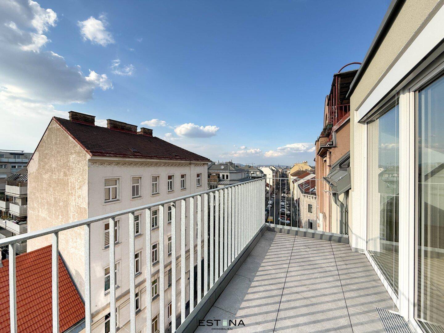 Geräumiger Balkon mit Fliesenboden und Blick auf die umliegende Stadtbebauung.