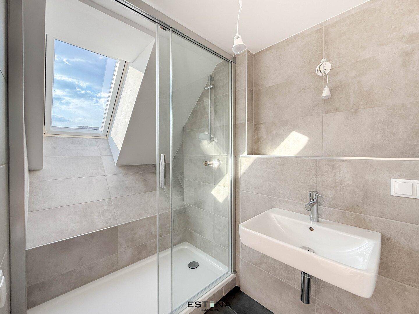 Modernes Badezimmer mit Dusche, Waschbecken und Dachfenster für natürliches Licht.