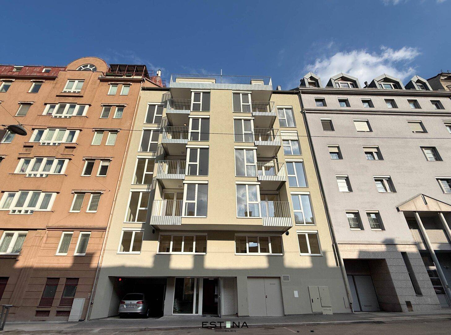 Moderne Gebäudefassade mit vielen Balkonen und großen Fenstern in urbaner Umgebung.