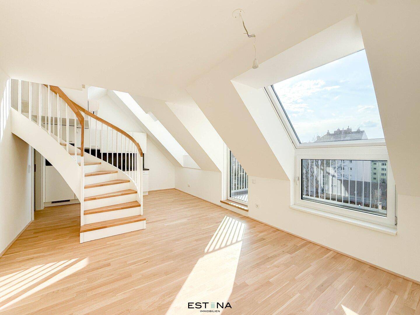 Helles Wohnzimmer im Dachgeschoss mit Holzparkett, Wendeltreppe und großen Dachfenstern.