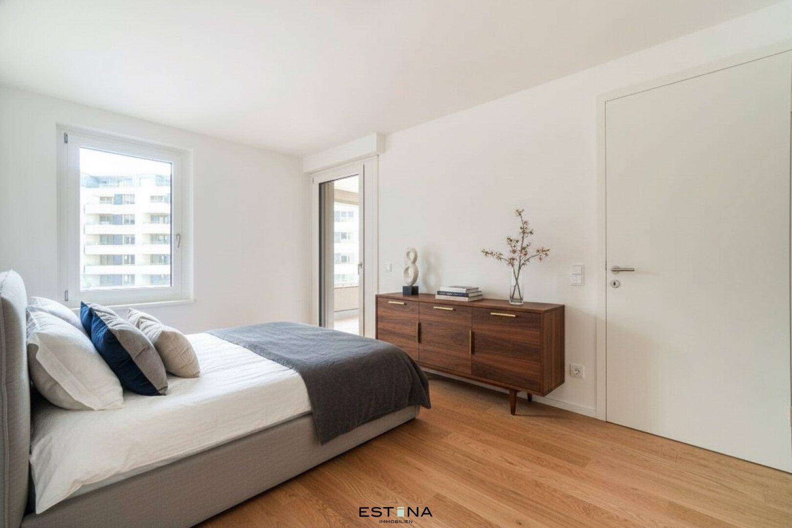 Gemütliches Schlafzimmer mit Holzboden, modernem Sideboard und Zugang zum Außenbereich.