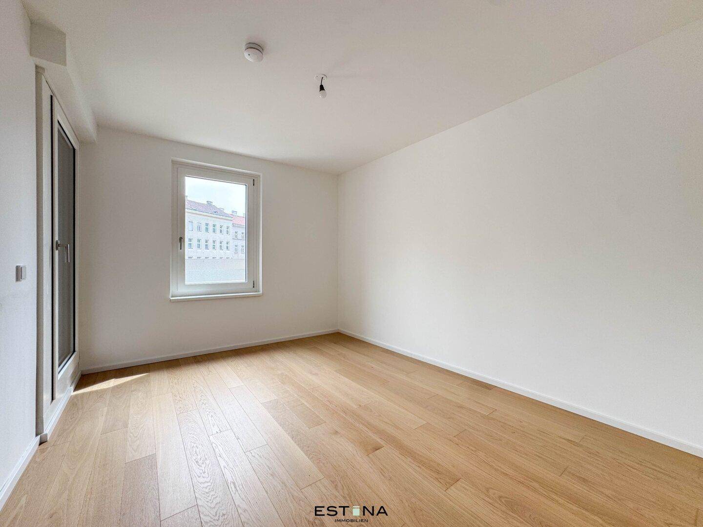 Ruhiges Schlafzimmer mit Holzboden und einem Fenster, das viel Tageslicht hereinlässt.