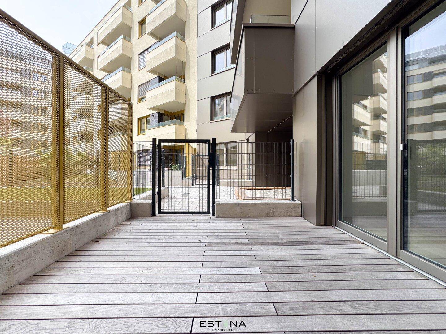 Private Terrasse mit Holzboden und Metallzaun, umgeben von moderner Architektur.