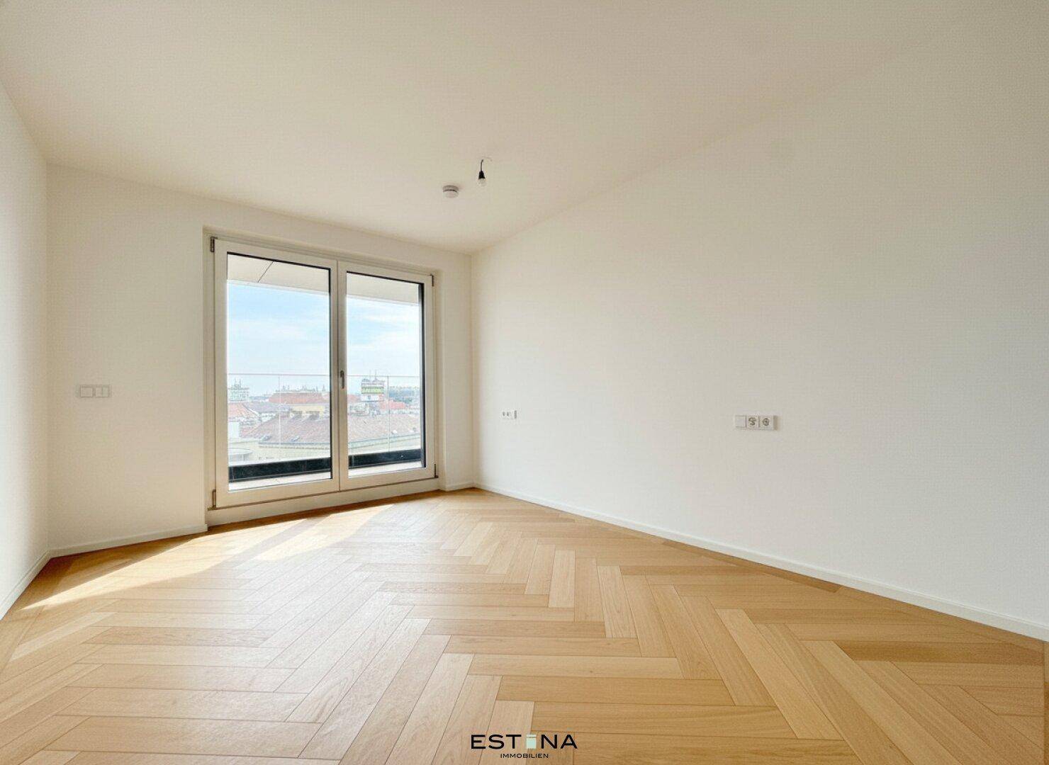 Helles Schlafzimmer mit Fischgrätparkett und Zugang zu einem Balkon, ideal für entspannte Morgenstunden.