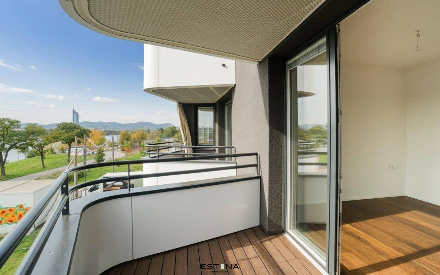 Moderner Balkon mit Holzboden und Zugang zu einem hellen Innenraum, mit Flussblick.