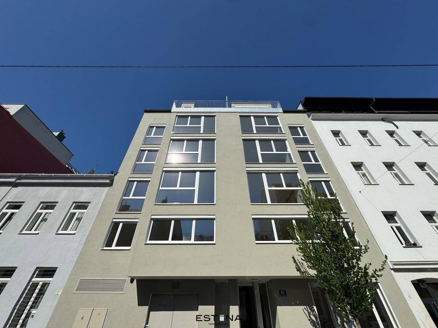 Moderne Gebäudefassade mit vielen Fenstern und klaren Linien unter blauem Himmel.