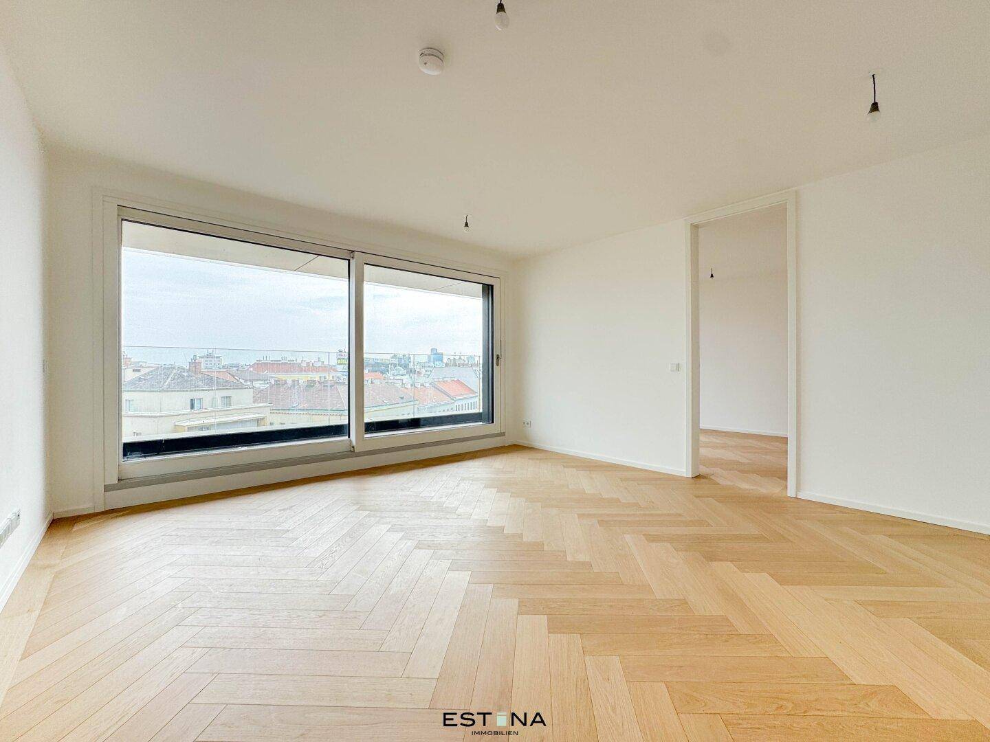Geräumiges Wohnzimmer mit großen Fenstern und Blick auf die Stadt, ausgestattet mit elegantem Fischgrätparkett.