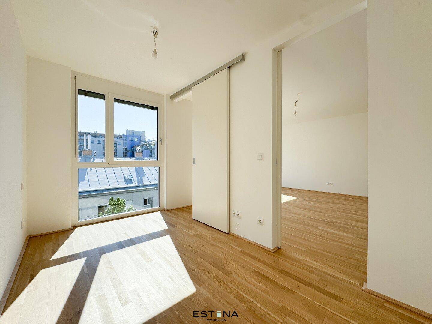 Helles Schlafzimmer mit Holzboden, großen Fenstern und Schiebetür, ideal für eine moderne Einrichtung.