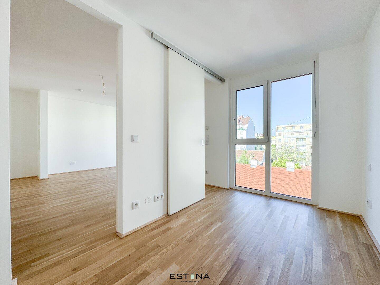 Lichtdurchfluteter Raum mit Holzboden und Schiebetür, ideal als Schlaf- oder Wohnbereich.