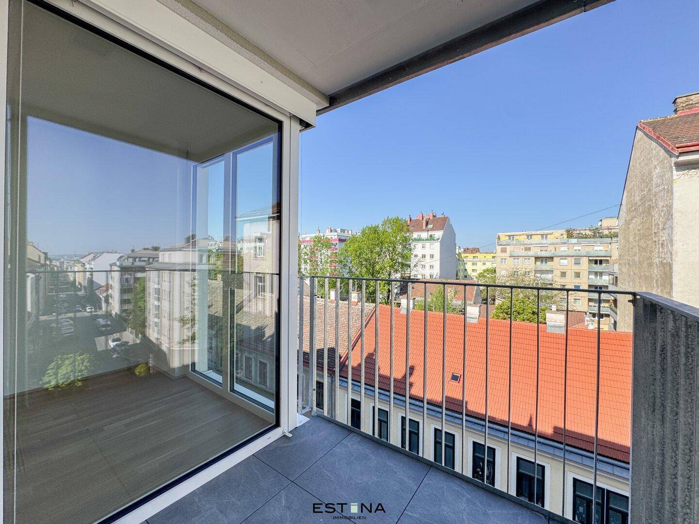 Geräumiger Balkon mit Fliesenboden und weitem Blick über die Dächer der Stadt.