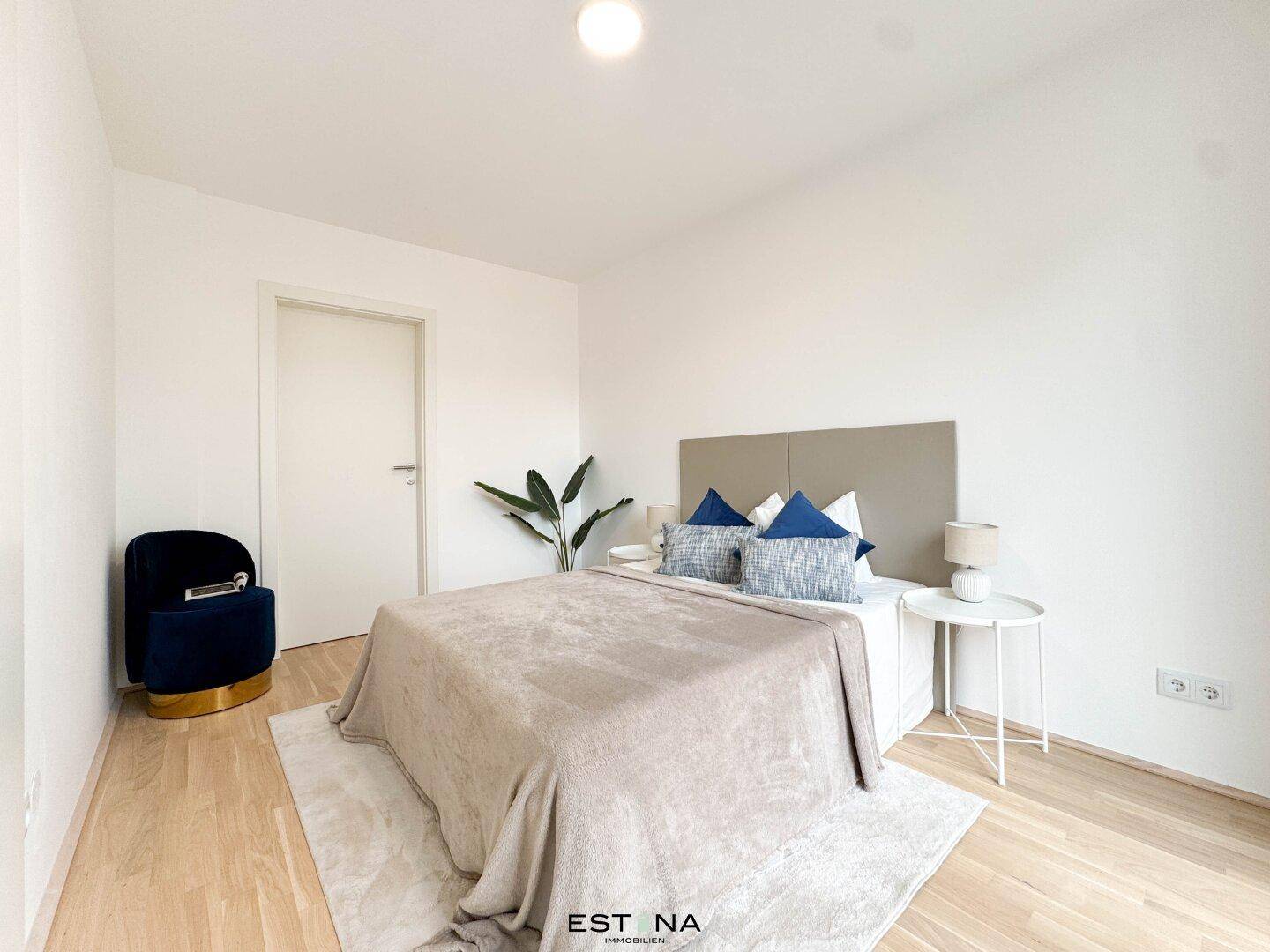 Helles Schlafzimmer mit Holzboden, modernem Bett und einem bequemen Sessel.