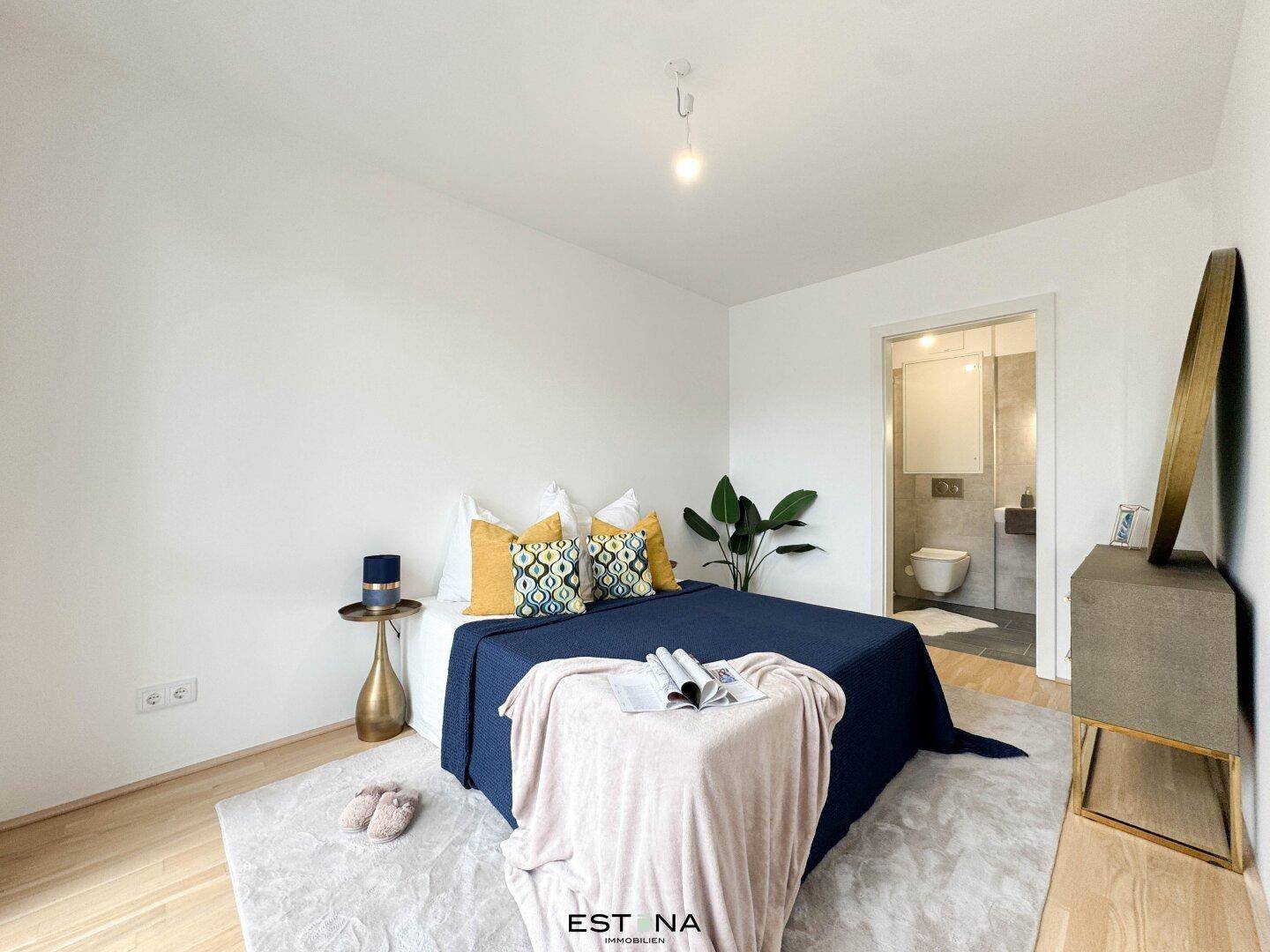 Modernes Schlafzimmer mit Holzboden, farbigen Akzenten und Zugang zum Badezimmer.