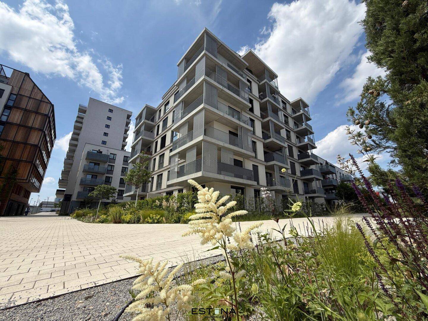 Moderne Wohnanlage mit mehreren Gebäuden, Balkonen und gepflegten Außenbereichen.