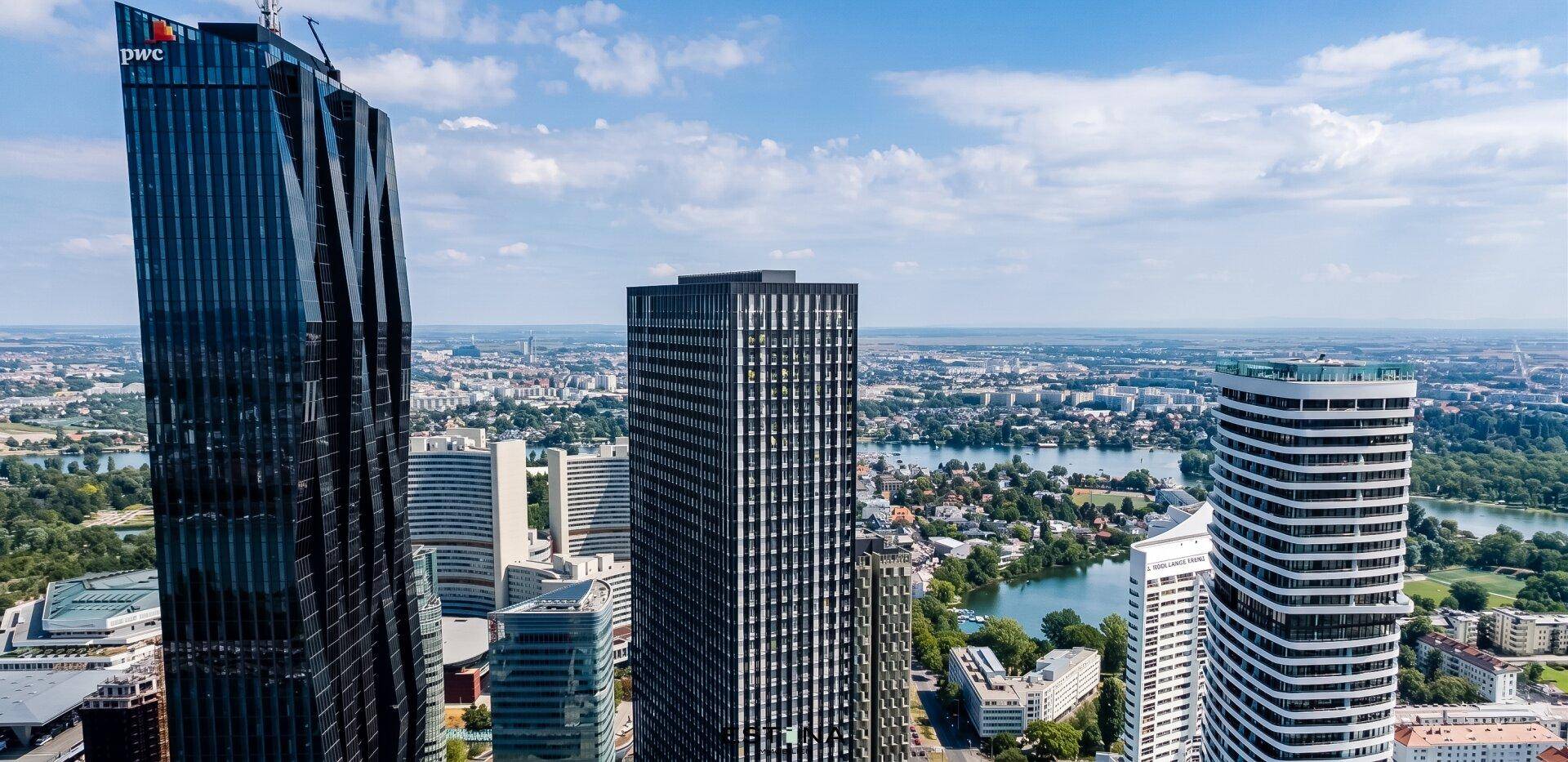 Luftaufnahme einer modernen Stadtlandschaft mit Hochhäusern, Fluss und Grünflächen.