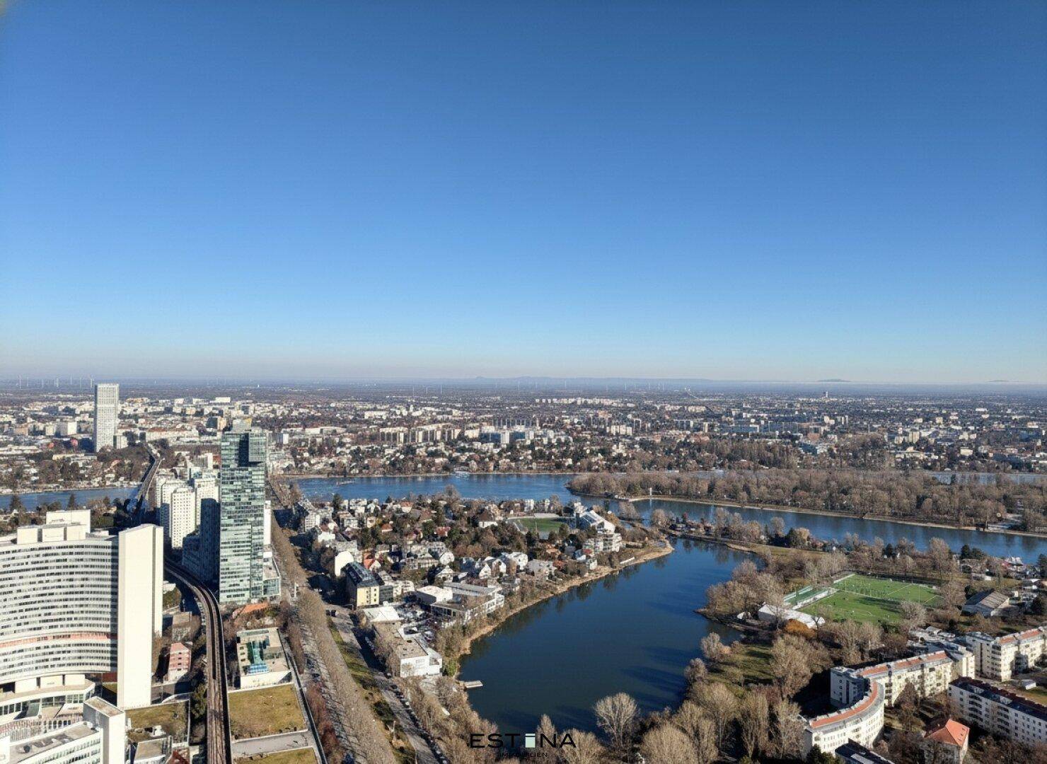 Weitläufiger Blick auf die Stadtlandschaft mit Fluss, Seen und urbaner Bebauung.