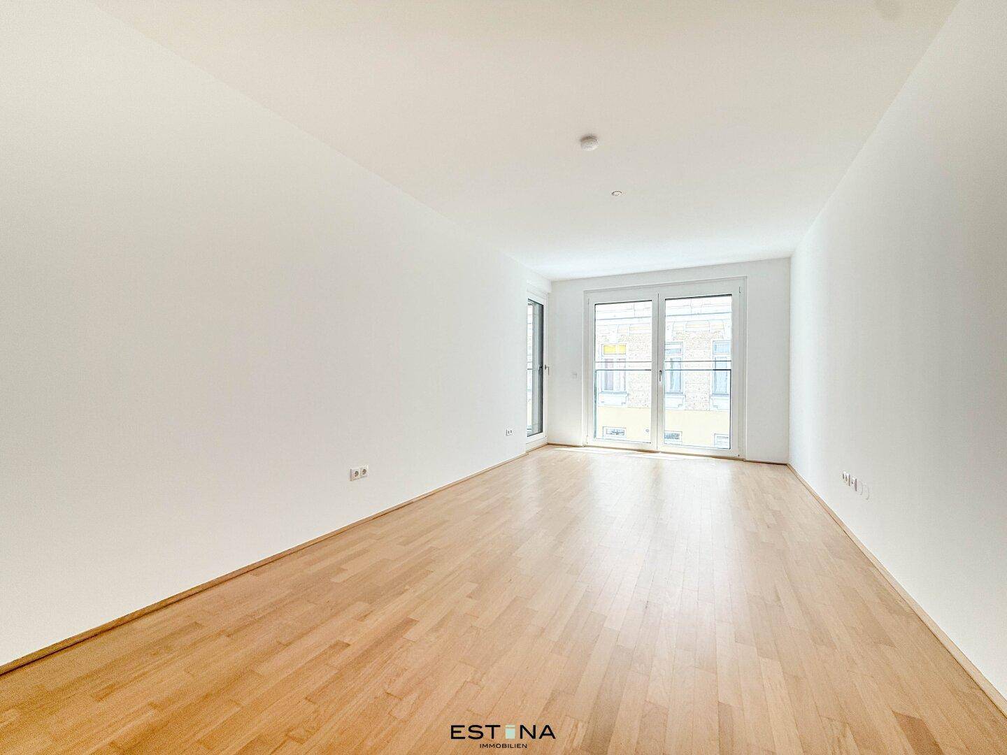Geräumiger, heller Raum mit Parkettboden und großen Fenstern, ideal als Wohn- oder Schlafzimmer.