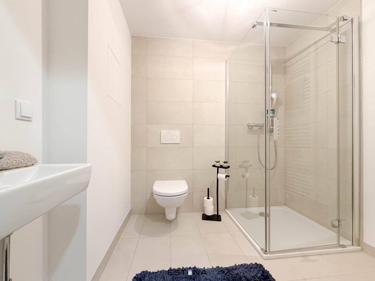 Helles Badezimmer mit Dusche, WC und modernem Waschbecken.