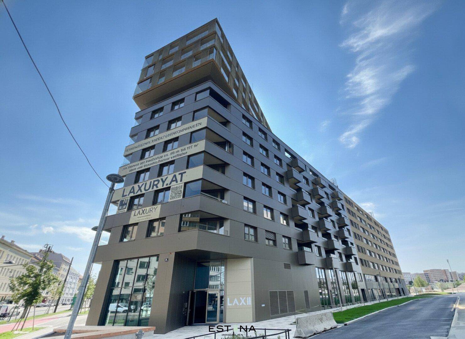 Modernes Wohngebäude mit markanter Architektur, großen Fenstern und zahlreichen Balkonen in urbaner Umgebung.