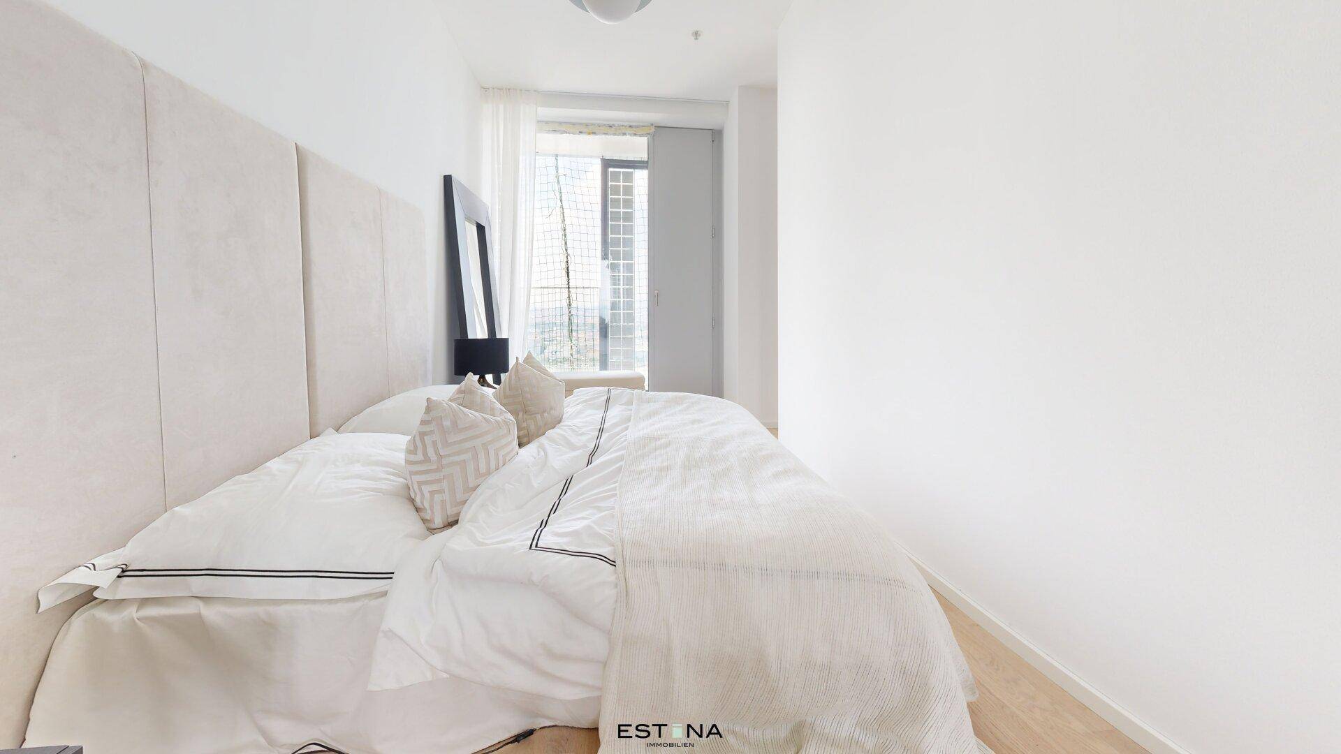 Helles Schlafzimmer mit großem Bett, minimalistischem Design und Zugang zu einem Balkon.