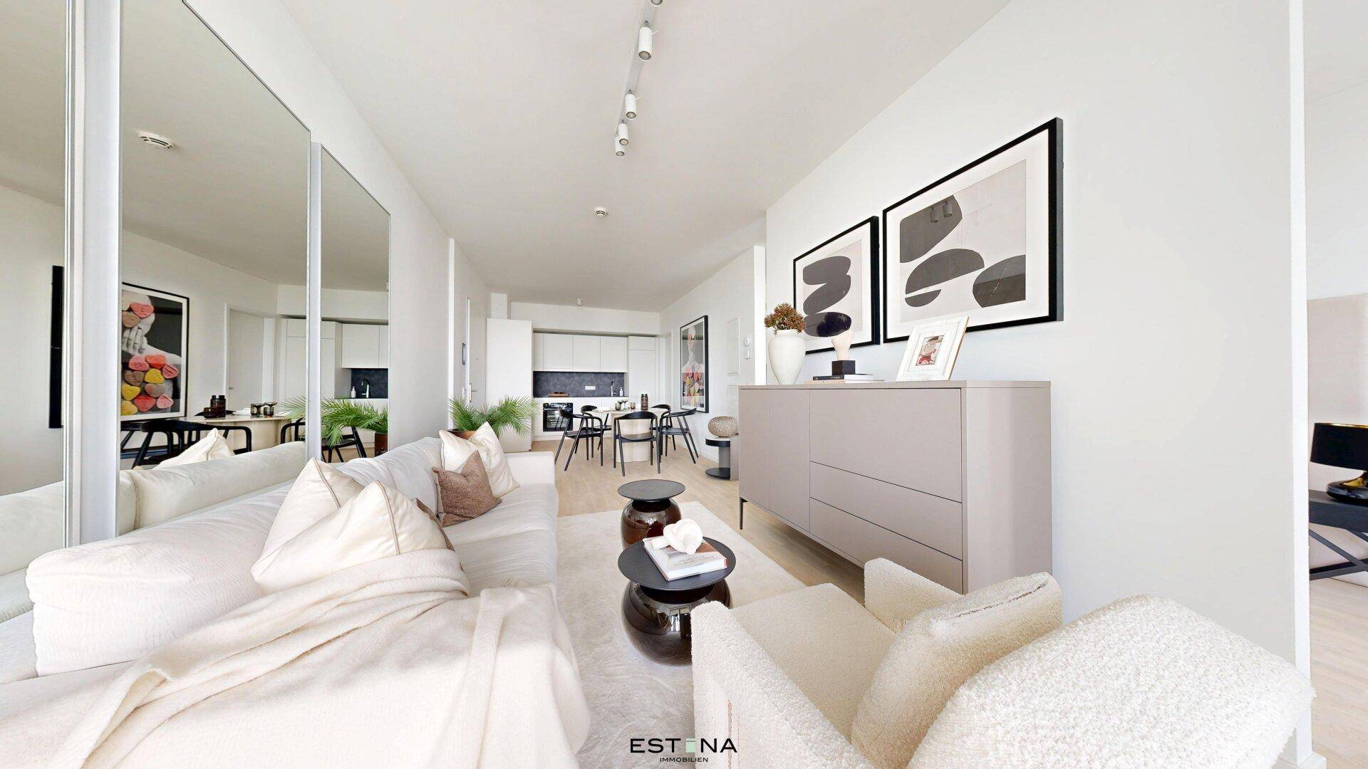 Geräumiges Wohnzimmer mit bequemer Couch, großen Spiegeln und offener Verbindung zur Küche.