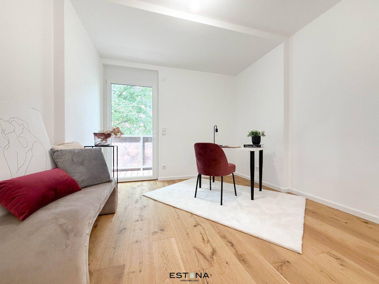 Ruhiges Arbeitszimmer mit Holzboden, Schreibtisch und Zugang zu einem kleinen Balkon.