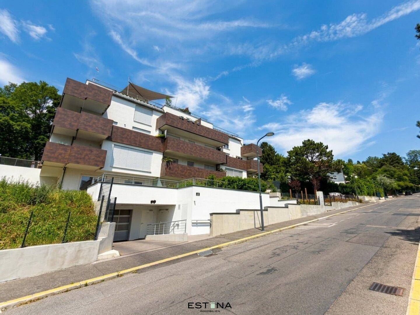 Ansicht der modernen Wohnanlage von der Straße aus, mit Tiefgaragenzufahrt und Grünflächen.
