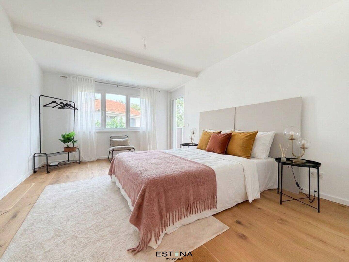 Geräumiges Schlafzimmer mit Holzboden, großem Bett und viel Tageslicht durch die Fenster.