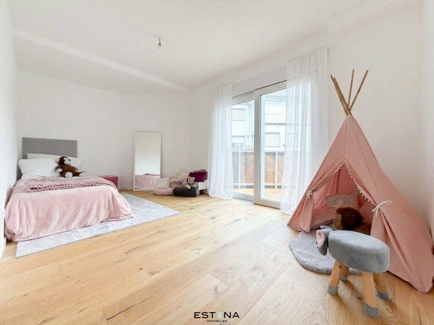 Helles Kinderzimmer mit Holzboden, Spielzelt und Zugang zu einem französischen Balkon.
