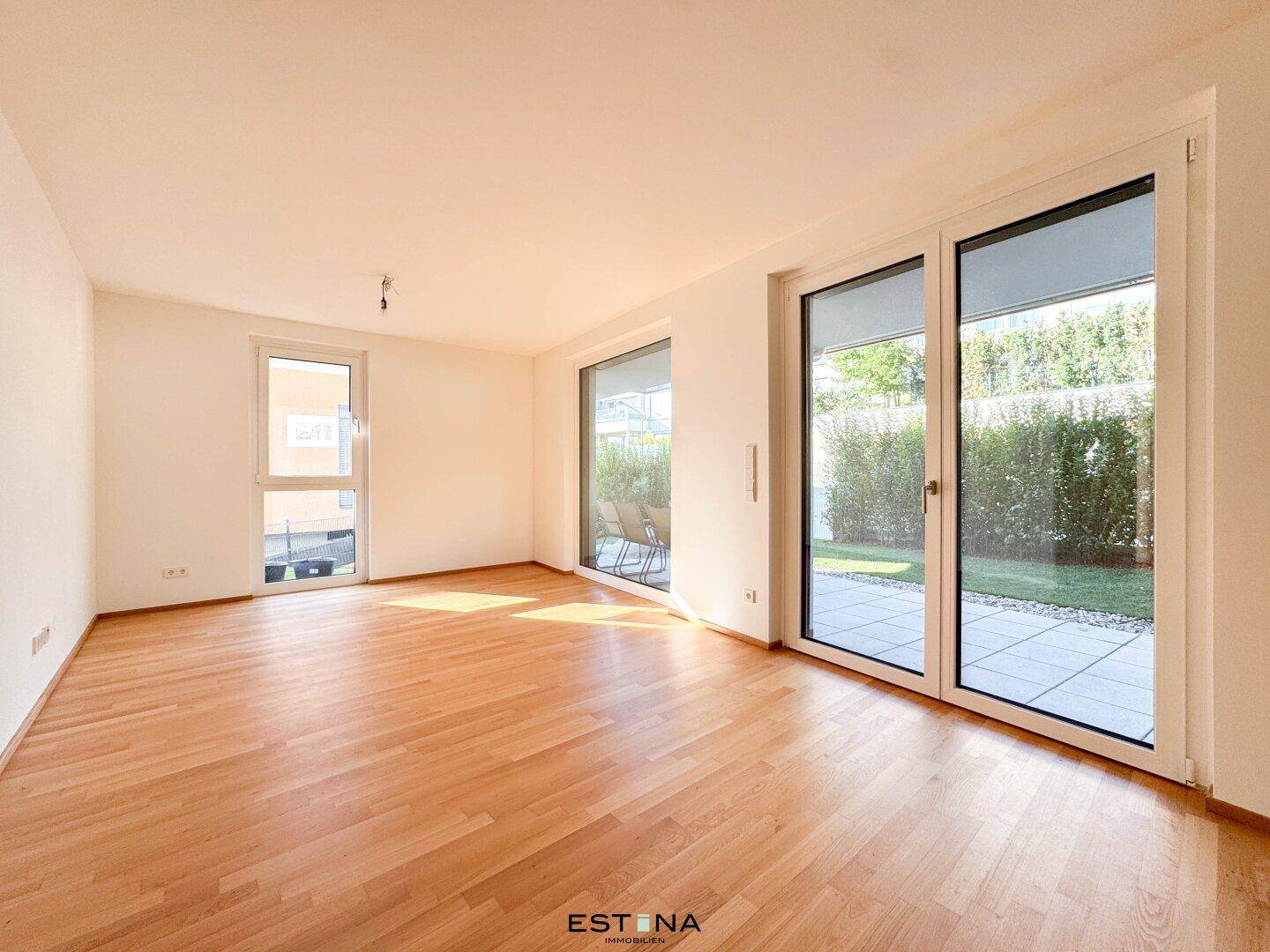 Lichtdurchfluteter Wohnbereich mit Holzboden und großen Fenstern zum Außenbereich.