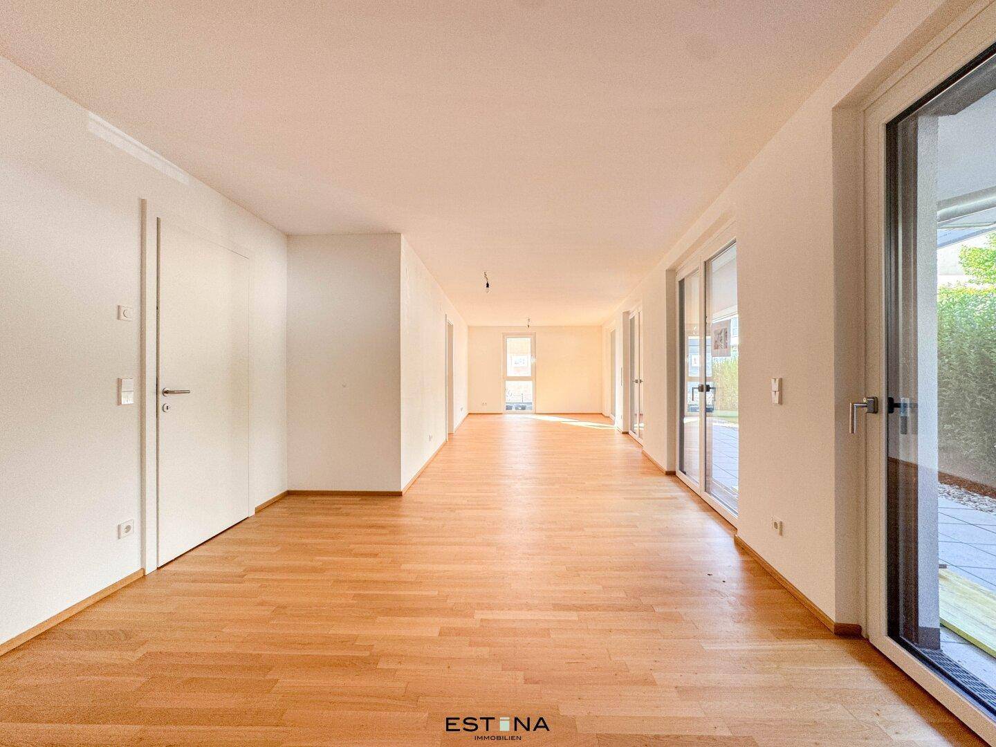 Heller, leerer Raum mit Parkettboden und Zugang zur Terrasse, ideal als Wohnzimmer.