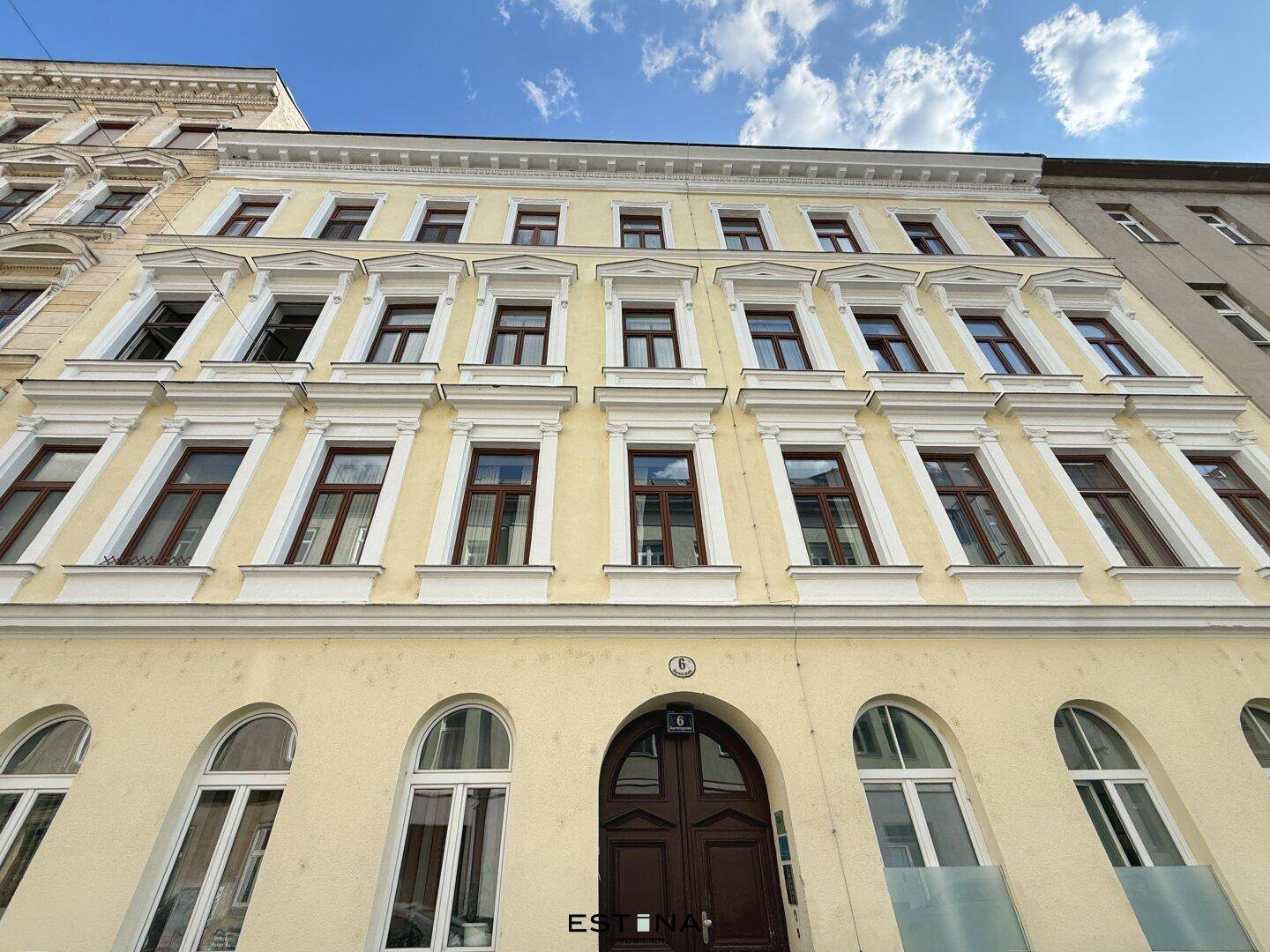 Klassische Fassade eines Altbaus mit vielen Fenstern und dekorativen Elementen, strahlt historischen Charme aus.