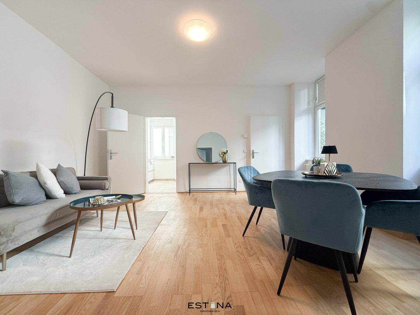 Heller Wohn- und Essbereich mit modernem Sofa, Esstisch und Parkettboden, ideal für geselliges Beisammensein.