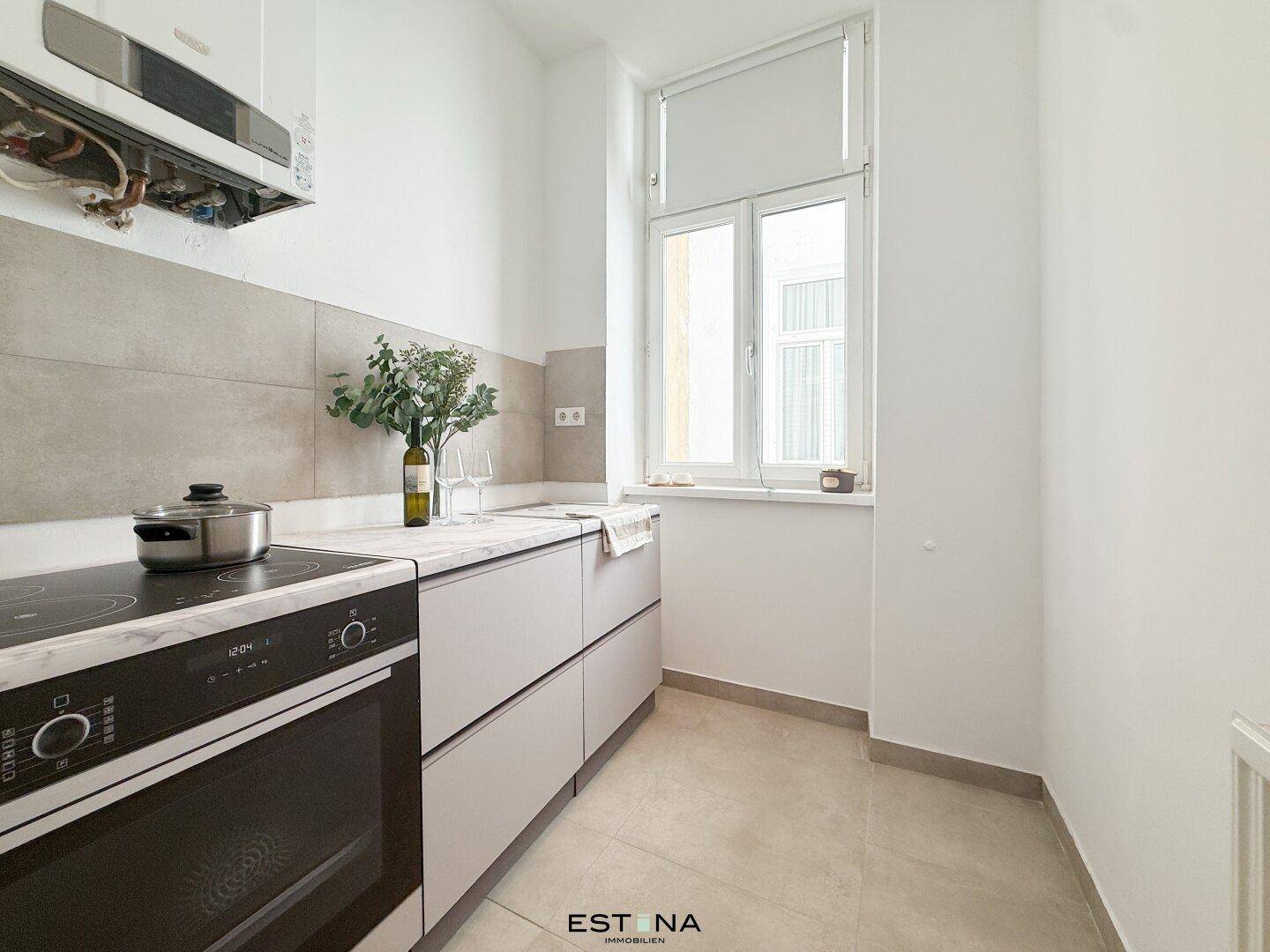 Funktionale Küche mit Herd, Arbeitsplatte und Fenster, bietet ausreichend Platz für kulinarische Aktivitäten.