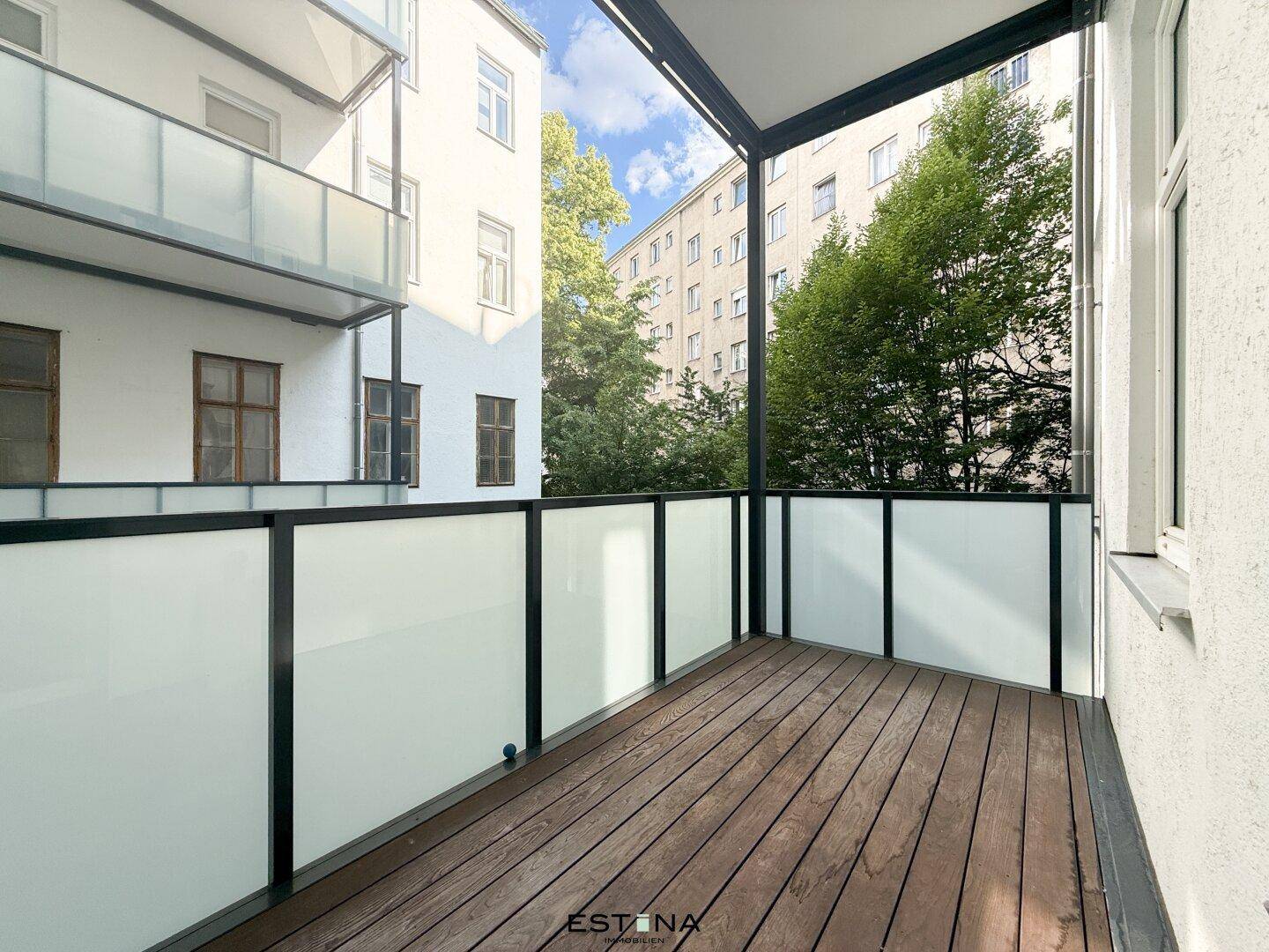 Moderner Balkon mit Holzboden und Glasgeländer, bietet einen angenehmen Außenbereich zum Entspannen.