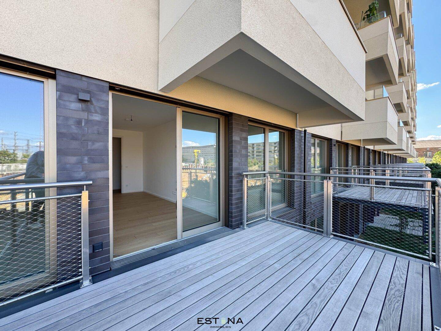 Moderner Balkon mit Holzdeck und Metallgeländer, mit Blick auf die Umgebung.