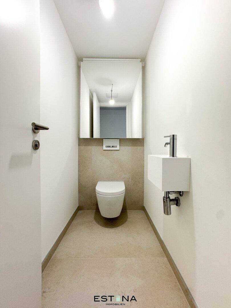 Modernes Gäste-WC mit wandhängender Toilette und kleinem Waschbecken.
