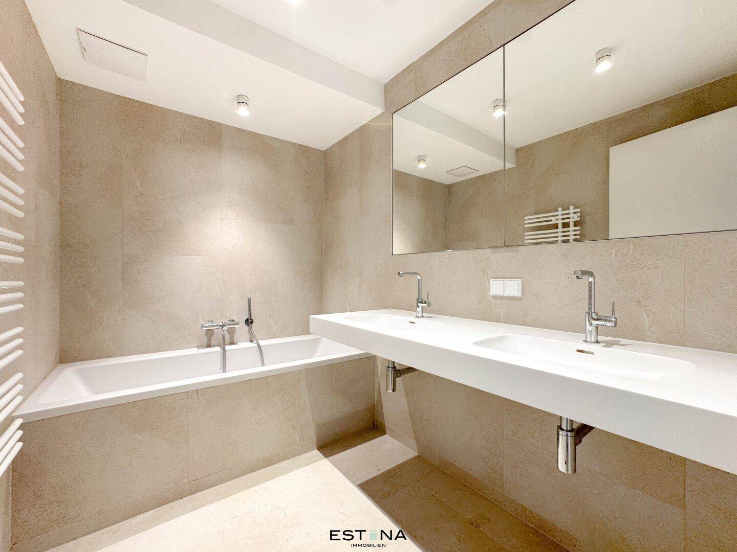 Modernes Badezimmer mit Badewanne, Doppelwaschbecken und großem Spiegelschrank.