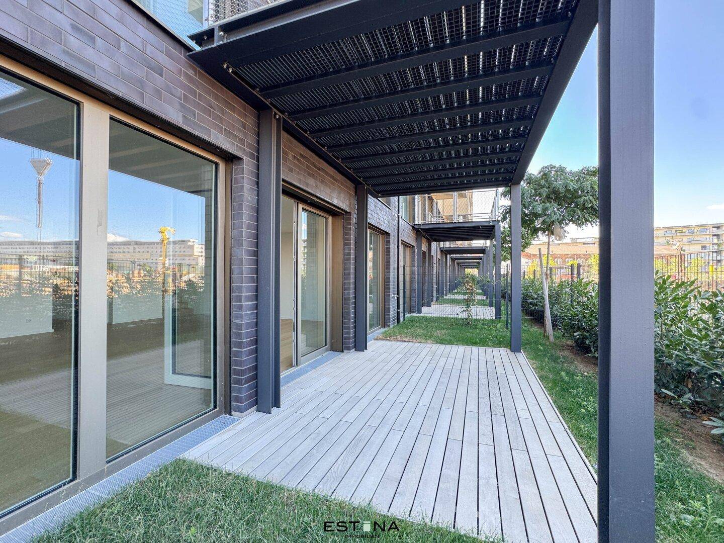 Moderne Terrasse mit Holzdeck und Überdachung, umgeben von Grünflächen.